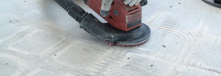 Person schleift Betonboden mit Schleifmaschine